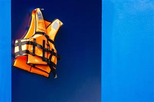 Neon orange life vest hanging on a wall.